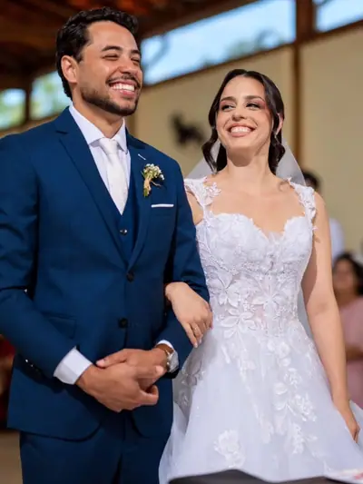 Noivos sorrindo de braços dados na entrada do salão