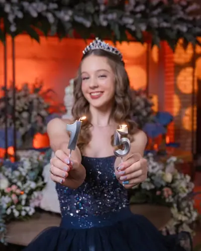 Debutante de coroa e vestido azul segurando as velas de 15 anos